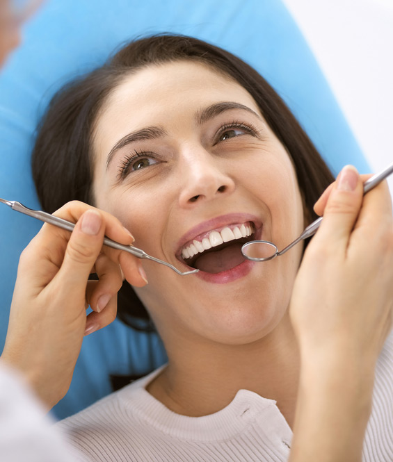 Young woman lying in dental chair with dental instruments in mouth