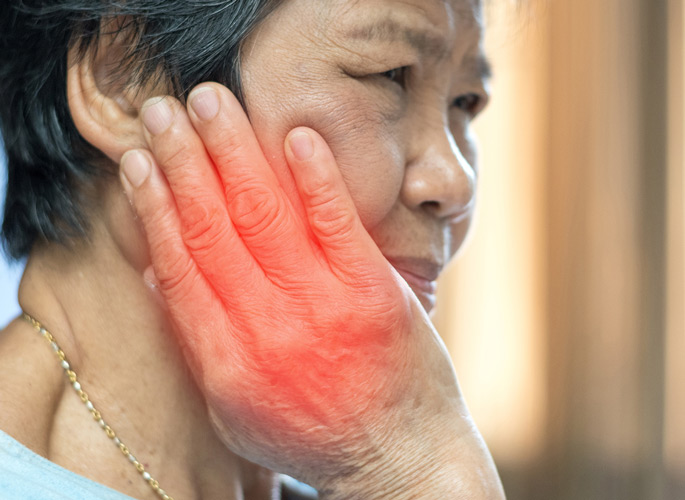 Older woman holding face with a red glow over hand